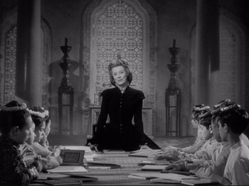 Movie still from “Anna and the King of Siam” (1946), directed by John Cromwell – A woman sitting in front of a group of people; Wide shot, High angle