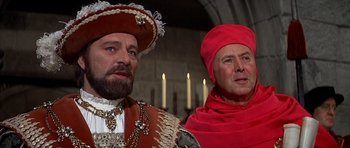 Movie still from “Anne of the Thousand Days” (1969), directed by Charles Jarrott – Two men dressed in medieval clothing and one is wearing a red hat; Close Up shot, Over the shoulder angle