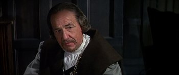 Movie still from “Anne of the Thousand Days” (1969), directed by Charles Jarrott – An older man wearing a brown coat and a chain; Close Up shot, Over the shoulder angle