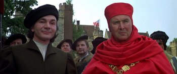 Movie still from “Anne of the Thousand Days” (1969), directed by Charles Jarrott – A group of people in medieval clothing standing in front of a castle; Close Up shot, Low angle