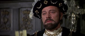 Movie still from “Anne of the Thousand Days” (1969), directed by Charles Jarrott – A person with a beard wearing a hat; Close Up shot, Over the shoulder angle