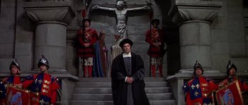 Movie still from “Anne of the Thousand Days” (1969), directed by Charles Jarrott – A man standing in front of a crucifixion; Wide shot, Low angle