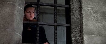 Movie still from “Anne of the Thousand Days” (1969), directed by Charles Jarrott – A woman sitting in front of a metal gate; Medium shot, Low angle