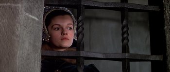 Movie still from “Anne of the Thousand Days” (1969), directed by Charles Jarrott – A young woman looking through a metal gate; Close Up shot, High angle