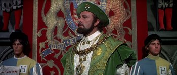 Movie still from “Anne of the Thousand Days” (1969), directed by Charles Jarrott – A man dressed in a green and gold outfit; Medium shot, Over the shoulder angle