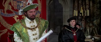 Movie still from “Anne of the Thousand Days” (1969), directed by Charles Jarrott – A man dressed as an elizabethan king holding a roll of paper; Medium shot, Over the shoulder angle