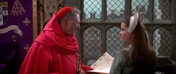 Movie still from “Anne of the Thousand Days” (1969), directed by Charles Jarrott – A man in a red robe and a woman in a red dress; Medium shot, Over the shoulder angle