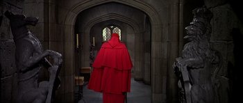 Movie still from “Anne of the Thousand Days” (1969), directed by Charles Jarrott – A person in a red robe in an archway of a building; Wide shot, High angle