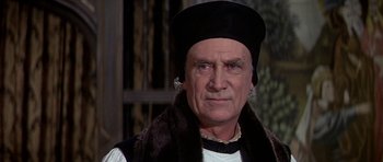 Movie still from “Anne of the Thousand Days” (1969), directed by Charles Jarrott – An older man wearing a black hat and a fur coat; Close Up shot, Over the shoulder angle