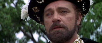 Movie still from “Anne of the Thousand Days” (1969), directed by Charles Jarrott – A person with a beard wearing a hat; Close Up shot, Over the shoulder angle