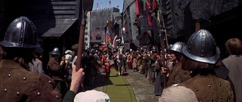 Movie still from “Anne of the Thousand Days” (1969), directed by Charles Jarrott – A group of people standing on top of a brick road; Wide shot, High angle