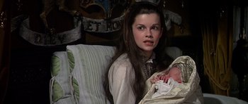 Movie still from “Anne of the Thousand Days” (1969), directed by Charles Jarrott – A woman sitting next to a baby on a couch; Close Up shot, High angle
