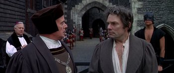 Movie still from “Anne of the Thousand Days” (1969), directed by Charles Jarrott – Two men in medieval garb standing next to each other in front of a castle; Close Up shot, Over the shoulder angle