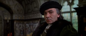 Movie still from “Anne of the Thousand Days” (1969), directed by Charles Jarrott – An older man wearing a black hat and a fur coat; Close Up shot, Over the shoulder angle