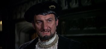 Movie still from “Anne of the Thousand Days” (1969), directed by Charles Jarrott – A person with a beard wearing a hat; Close Up shot, Over the shoulder angle