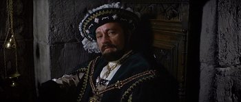 Movie still from “Anne of the Thousand Days” (1969), directed by Charles Jarrott – A man with a beard wearing a hat and a suit; Close Up shot, High angle