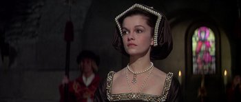 Movie still from “Anne of the Thousand Days” (1969), directed by Charles Jarrott – A woman in a black and gold dress with pearls; Close Up shot, Over the shoulder angle