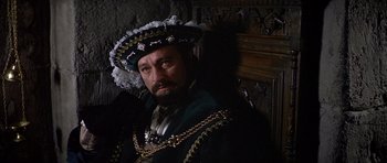 Movie still from “Anne of the Thousand Days” (1969), directed by Charles Jarrott – A man in a green and black suit with a beard; Close Up shot, Over the shoulder angle