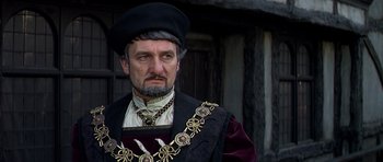 Movie still from “Anne of the Thousand Days” (1969), directed by Charles Jarrott – A person wearing a suit and a hat; Close Up shot, Over the shoulder angle