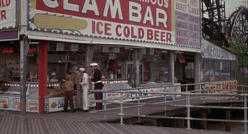 Movie still from “Annie Hall” (1977), directed by Woody Allen – A group of men standing on a pier near a building; Wide shot, High angle