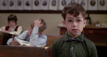 Movie still from “Annie Hall” (1977), directed by Woody Allen – A boy with glasses and a tie is sitting at a desk with another boy; Close Up shot, Over the shoulder angle