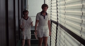 Movie still from “Annie Hall” (1977), directed by Woody Allen – Two men are walking down a hallway holding rackets; Medium shot, Low angle