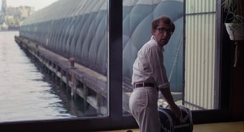 Movie still from “Annie Hall” (1977), directed by Woody Allen – A man standing in front of a window with water behind him; Medium shot, Over the shoulder angle