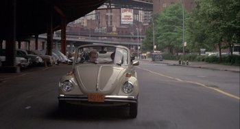 Movie still from “Annie Hall” (1977), directed by Woody Allen – An old vw bug driving down the street in the city; Wide shot, Over the shoulder angle