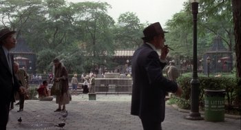 Movie still from “Annie Hall” (1977), directed by Woody Allen – An older man smoking a cigarette in a public park; Wide shot, High angle
