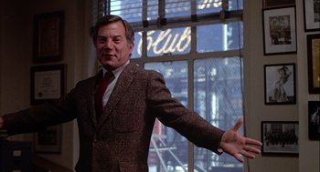 Movie still from “Annie Hall” (1977), directed by Woody Allen – A man in a suit and tie standing in front of a window; Medium shot, Low angle