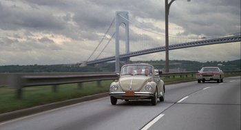 Movie still from “Annie Hall” (1977), directed by Woody Allen – An old volkswagon beetle driving on a highway; Wide shot, High angle