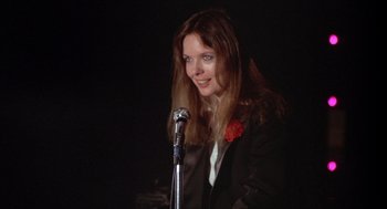 Movie still from “Annie Hall” (1977), directed by Woody Allen – A woman in a black jacket is holding a microphone; Close Up shot, Low angle