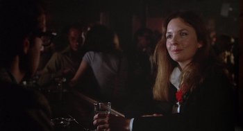 Movie still from “Annie Hall” (1977), directed by Woody Allen – A woman sitting at a table holding a glass of water; Close Up shot, Over the shoulder angle