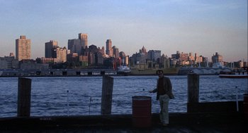 Movie still from “Annie Hall” (1977), directed by Woody Allen – A man standing next to the water near a pier; Extreme Wide shot, High angle