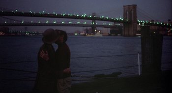 Movie still from “Annie Hall” (1977), directed by Woody Allen – Two people are kissing in front of a bridge; Wide shot, High angle