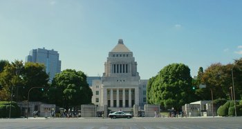 Movie still from “Antiporno” (2016), directed by Sion Sono – A car parked in front of a large building; Extreme Wide shot, Low angle