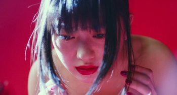 Movie still from “Antiporno” (2016), directed by Sion Sono – A young woman with black hair and red lipstick; Close Up shot, Low angle