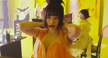 Movie still from “Antiporno” (2016), directed by Sion Sono – A woman in an orange dress with her hands behind her head; Close Up shot, Low angle