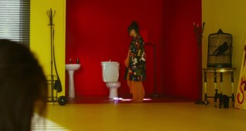 Movie still from “Antiporno” (2016), directed by Sion Sono – A woman standing in front of a toilet in a bathroom; Wide shot, Low angle
