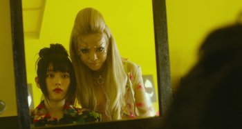 Movie still from “Antiporno” (2016), directed by Sion Sono – A woman with long blonde hair and a face make - up looking in a mirror; Close Up shot, Low angle