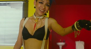 Movie still from “Antiporno” (2016), directed by Sion Sono – A woman in a black bra and a gold necklace; Medium shot, Overhead angle