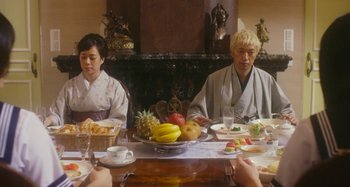 Movie still from “Antiporno” (2016), directed by Sion Sono – A group of people sitting around a table with food; Medium shot, Over the shoulder angle