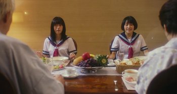 Movie still from “Antiporno” (2016), directed by Sion Sono – Two women sitting at a table with a bowl of fruit; Medium shot, Over the shoulder angle