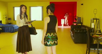 Movie still from “Antiporno” (2016), directed by Sion Sono – Two women are standing in a yellow room; Wide shot, Over the shoulder angle