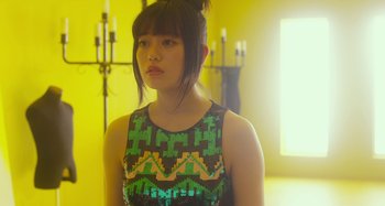 Movie still from “Antiporno” (2016), directed by Sion Sono – A young woman in a green and black dress; Close Up shot, Over the shoulder angle