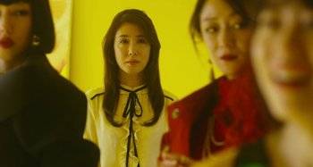 Movie still from “Antiporno” (2016), directed by Sion Sono – A woman standing in front of a yellow wall; Medium shot, Low angle