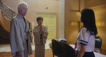 Movie still from “Antiporno” (2016), directed by Sion Sono – A group of people standing in a living room; Medium shot, Low angle