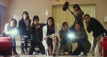 Movie still from “Antiporno” (2016), directed by Sion Sono – A group of women taking pictures of a person; Wide shot, Low angle