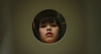 Movie still from “Antiporno” (2016), directed by Sion Sono – A woman is looking into the mirror of a bathroom; Extreme Close Up shot, Overhead angle