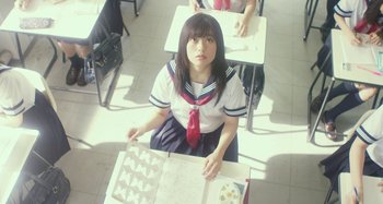 Movie still from “Antiporno” (2016), directed by Sion Sono – A girl in a school uniform sitting at a desk; Medium shot, High angle